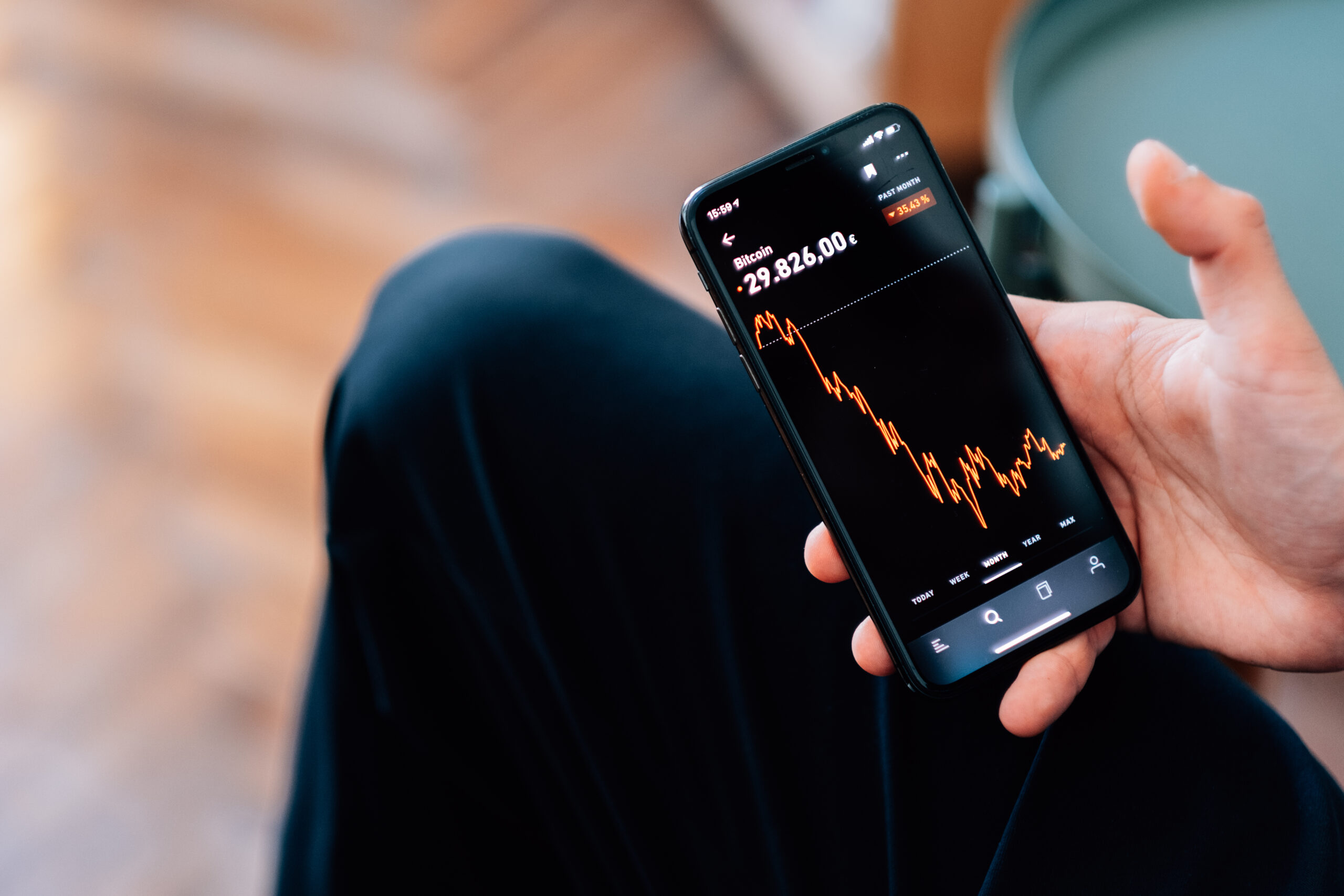 selective focus shot of male hand holding a smartphone with cryptocurrencies statistics on screen
